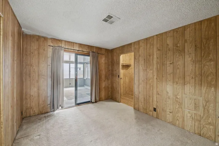 Carpeted interior space featuring wood-paneled walls and a textured ceiling