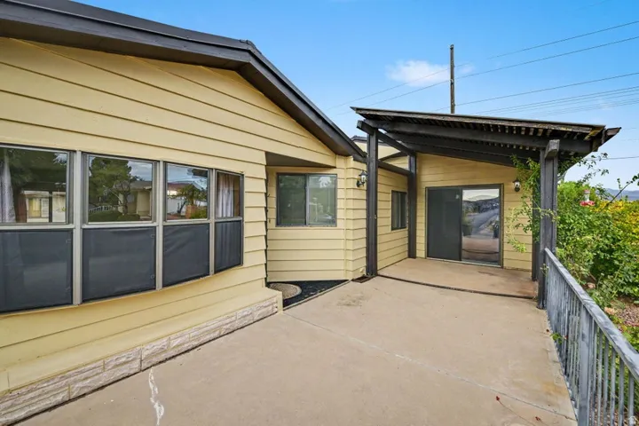 Exterior featuring horizontal siding, a concrete patio, a dark-stained pergola, a sliding glass door, and multiple windows