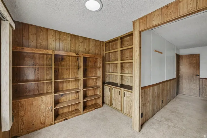 Room featuring extensive wood-paneling, built-in shelving units, and integrated cabinetry