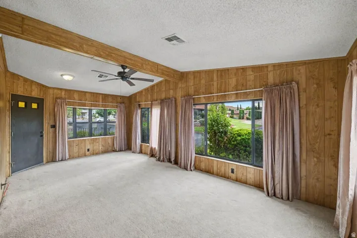 Spacious interior featuring wood-finish wall paneling, light-toned carpeting, and multiple windows