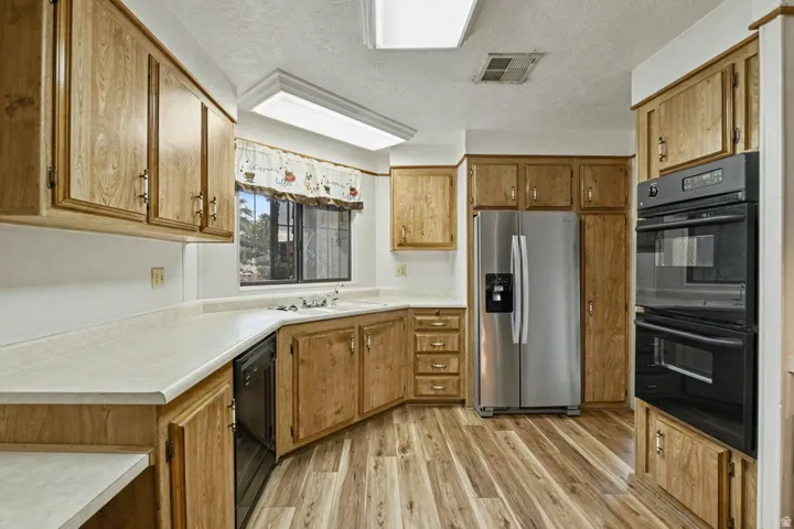Kitchen featuring wood-finish cabinetry, light-toned countertops, and wood-finish flooring
