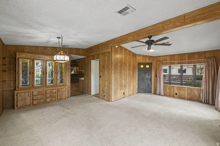 Living area featuring wood-paneled walls and a light-toned carpet