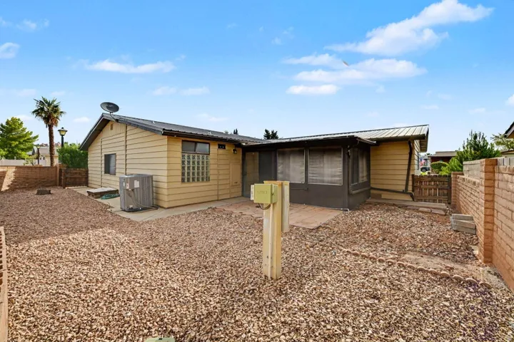 Rear exterior featuring a screened patio, a gravel yard, and a light-colored siding facade