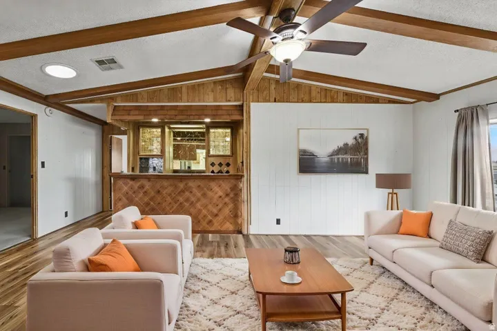 Vaulted ceiling with exposed wood beams and a ceiling fan