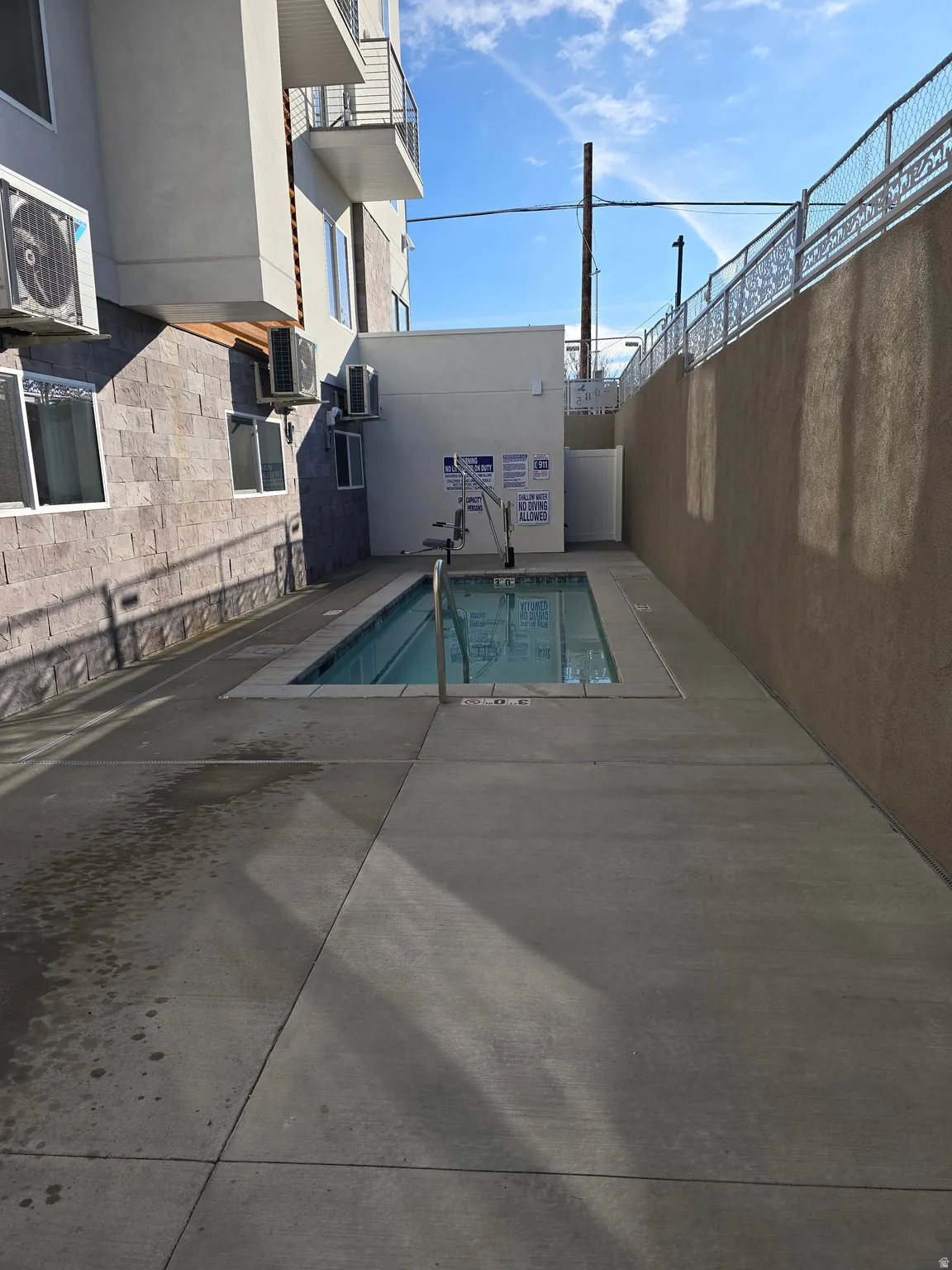 Outdoor swimming pool with integrated accessibility lift, surrounded by concrete decking