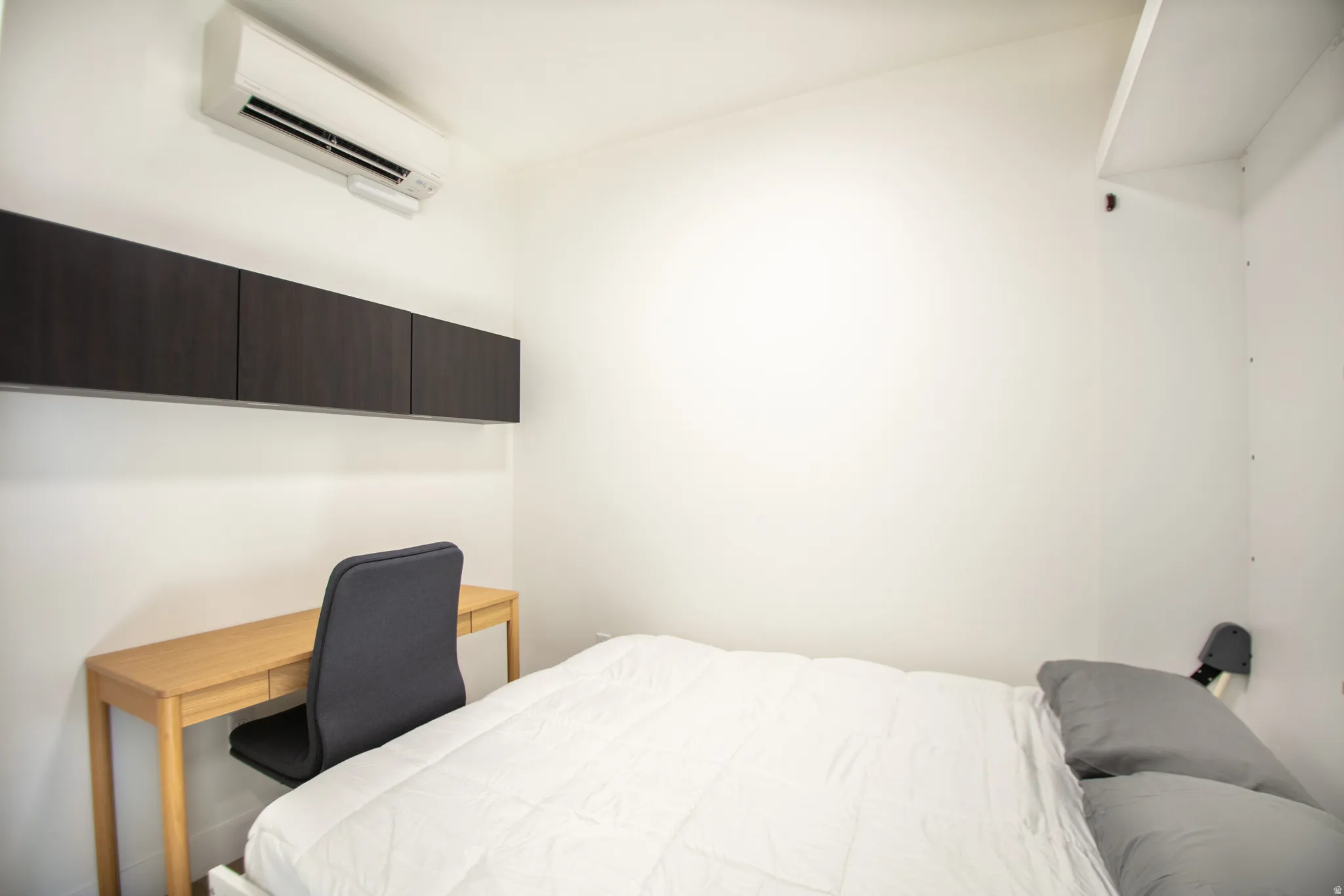 White walls with dark wood-finish cabinetry and an integrated wall-mounted air conditioning unit