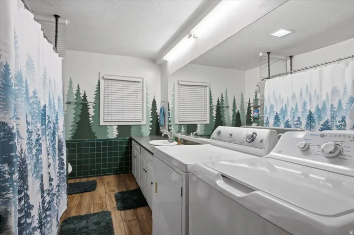 Bathroom featuring wood-finish flooring, a vanity with integrated sink, and a tiled shower area