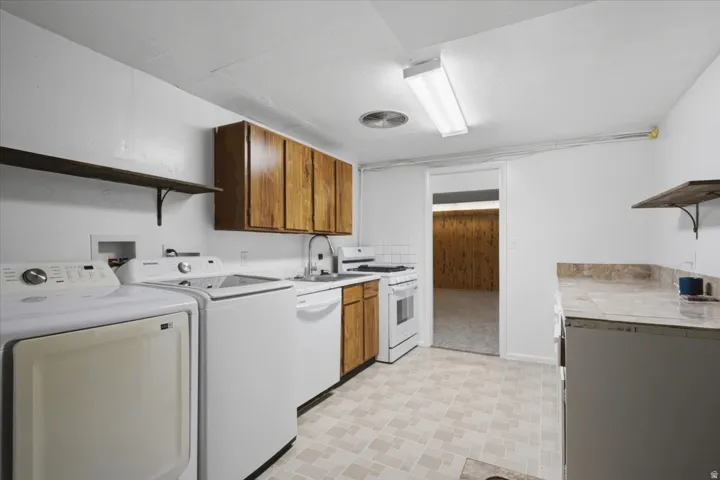 Utility room featuring a patterned tile-finish floor, wood-finish cabinetry, and a countertop with an integrated sink