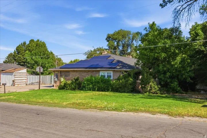 Brick exterior residence featuring a dark shingle roof with integrated solar panels