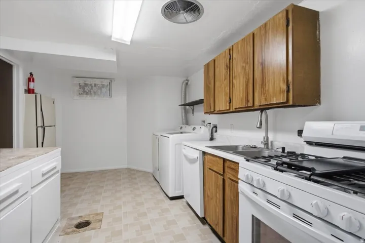 Utility room with a gas range, dishwasher, and sink