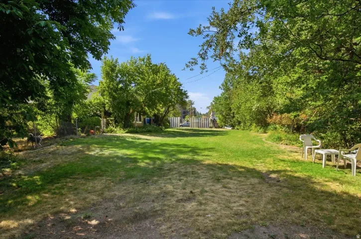 Expansive manicured lawn framed by mature shade trees and established landscaping