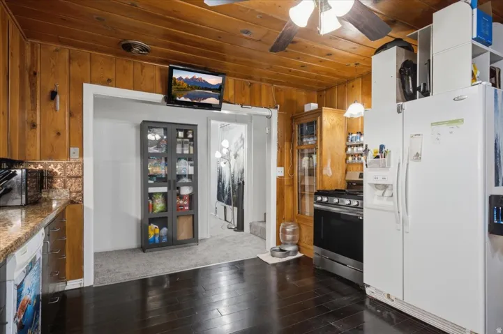Kitchen featuring wood-paneled walls and ceiling, dark wood-finish flooring, and a ceiling fan with integrated lighting