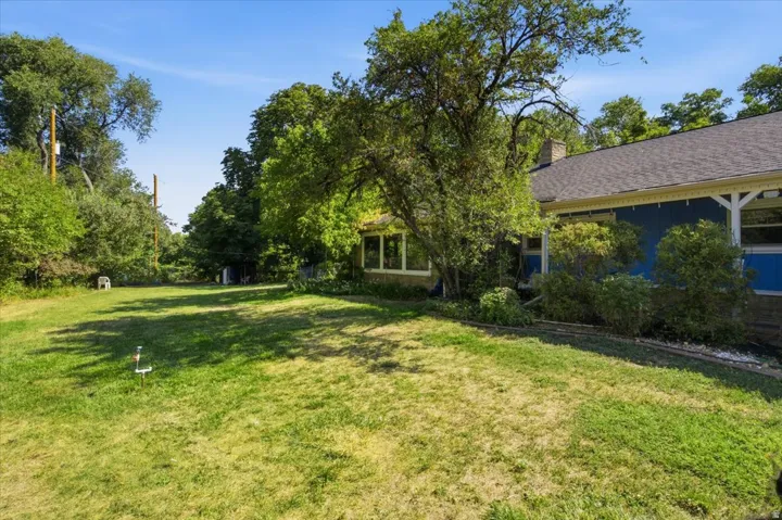 Expansive green space featuring mature trees and a stone-clad foundation