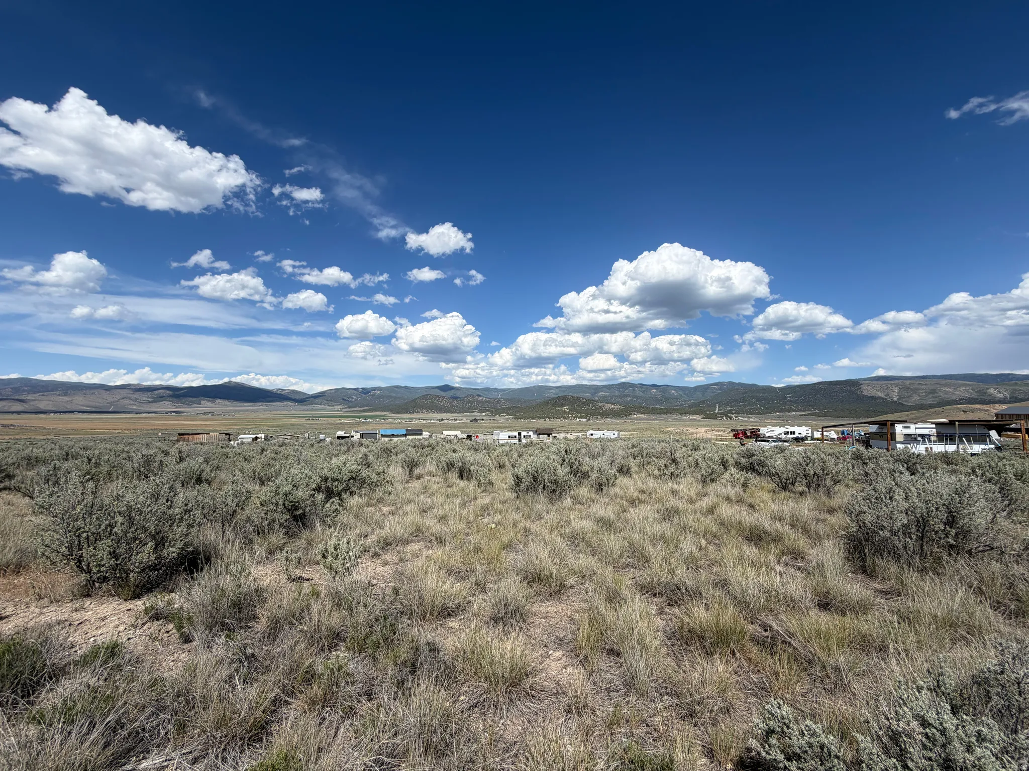 Expansive open terrain featuring natural vegetation, distant mountainous topography, and a clear sky