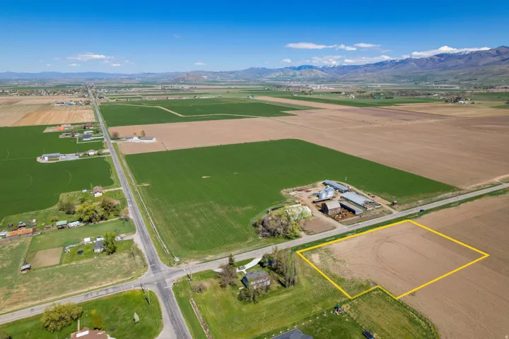 Expansive agricultural land featuring a visible lot boundary, surrounded by cultivated fields and distant mountain ranges