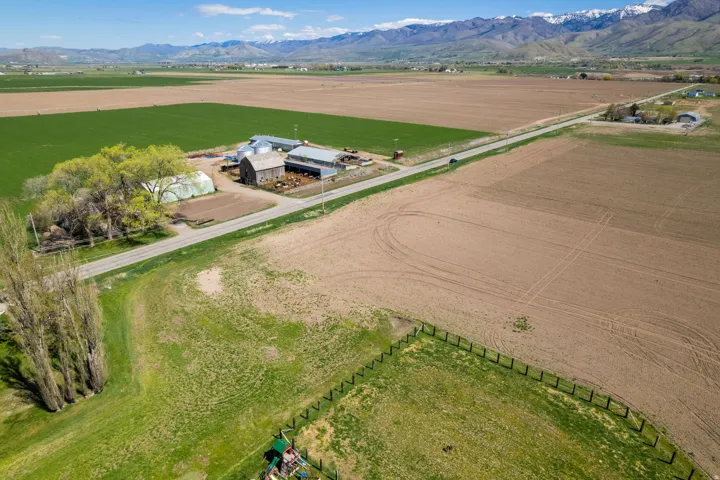 Agricultural property featuring multiple outbuildings, cultivated fields, and a greenhouse structure