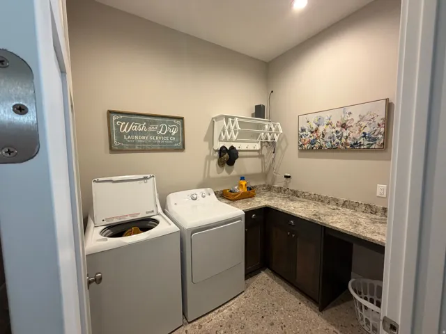 Dedicated laundry room with textured flooring, dark wood-finish cabinetry, and light-toned countertops