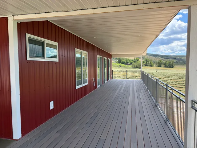 Expansive covered deck featuring composite decking, gray metal railing, and recessed lighting
