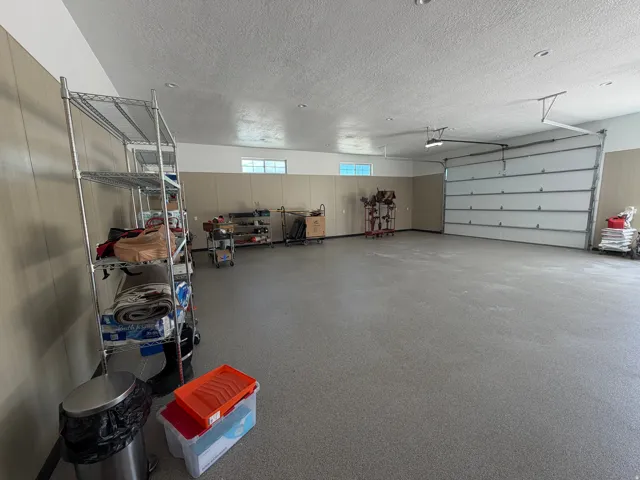 Spacious garage featuring a sectional garage door, light-toned paneling, recessed lighting, and a textured concrete floor