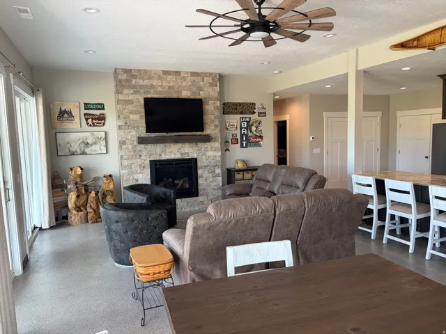 Living area featuring a floor-to-ceiling stacked stone fireplace with a wood mantle, a ceiling fan, recessed lighting, and direct patio access