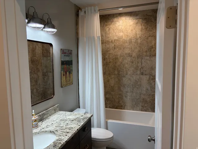 Bathroom featuring a vanity with a white undermount sink and a light-toned granite countertop