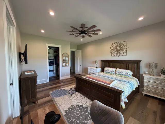 Spacious bedroom featuring wood-finish flooring, recessed lighting, and a contemporary ceiling fan