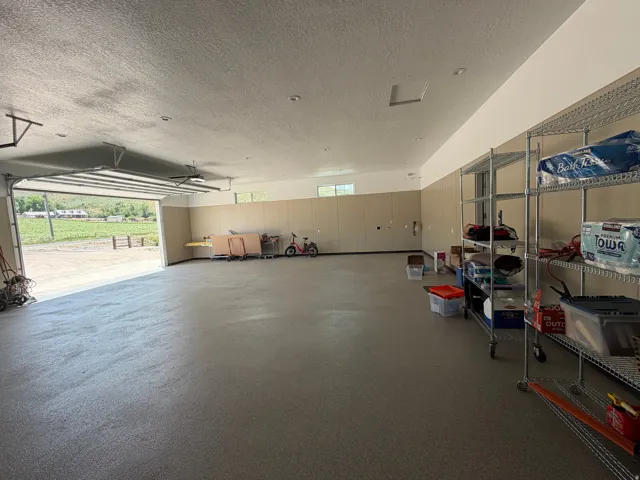 Spacious garage with epoxy flooring, equipped with an automatic overhead door and recessed lighting