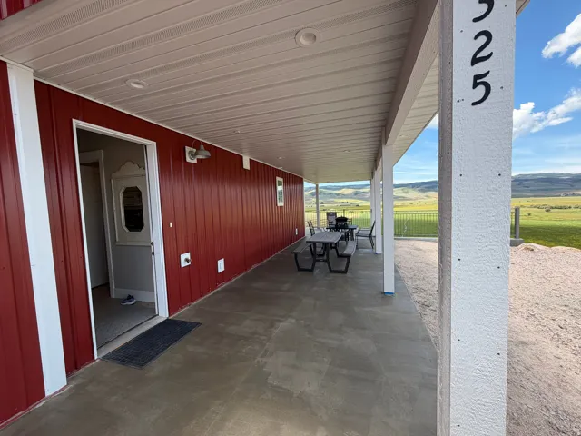 Expansive covered porch featuring a concrete surface, white columns, and a red exterior wall