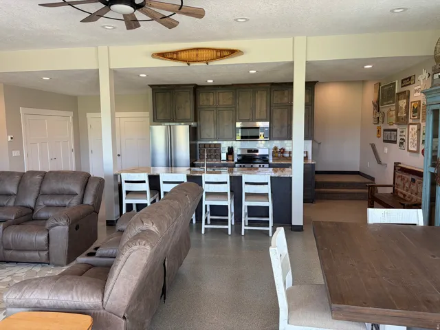 Open-concept kitchen featuring wood-finish cabinetry, stainless steel appliances, and a granite-look island with seating