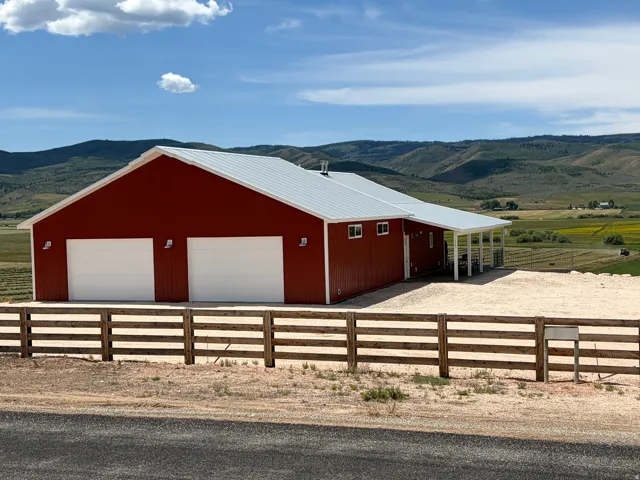 Red metal-sided structure featuring a white corrugated metal roof and two large garage doors