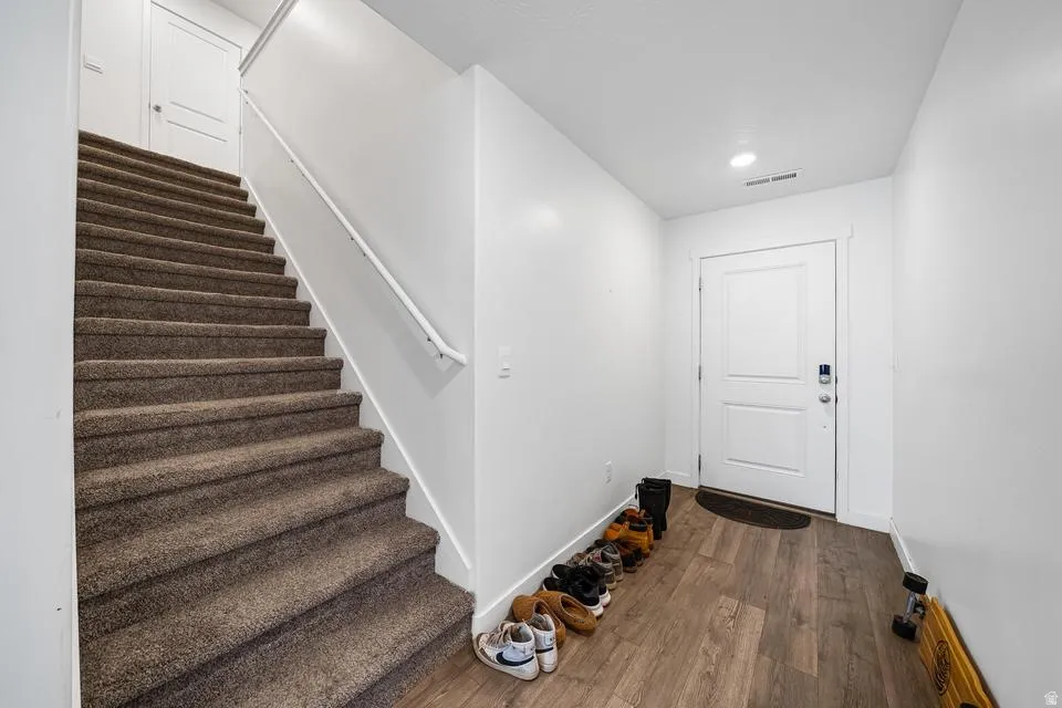 Foyer with wood-finish flooring, a white paneled door, and a recessed ceiling light