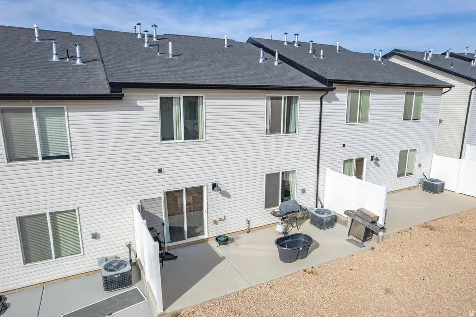 Rear exterior featuring light-colored siding, dark shingle roofing, and black gutters