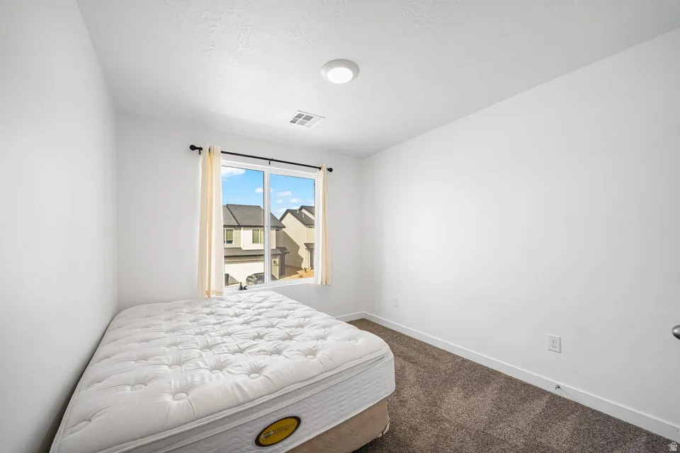 Bright room featuring white walls, a large window with white trim, and neutral carpet flooring