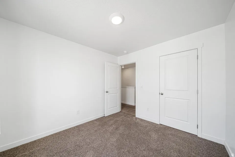 Room featuring neutral-toned carpet, white walls, and a flush-mount ceiling light