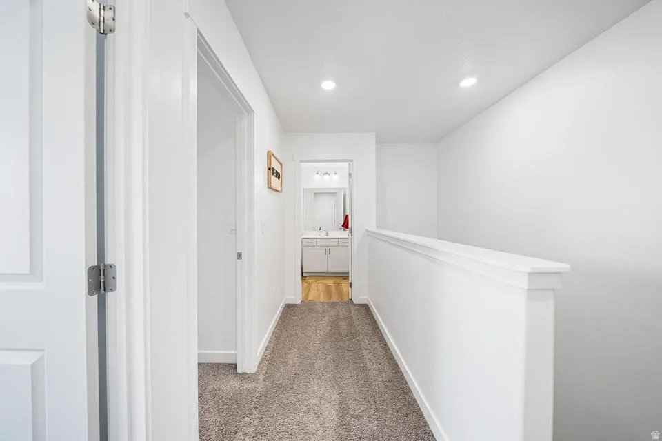 Second-story hallway featuring neutral-toned carpeting and a white half-wall railing