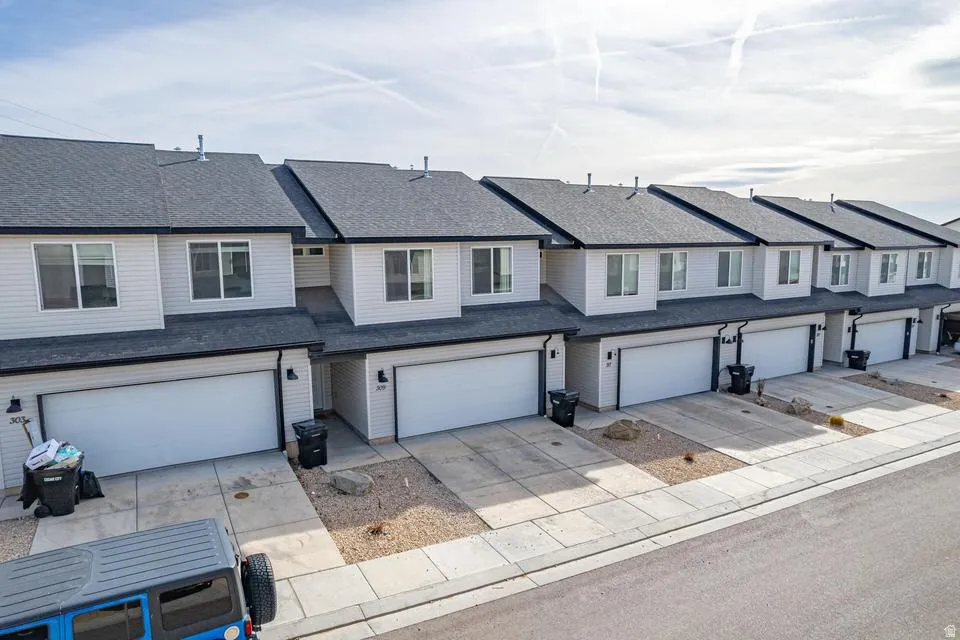 Modern townhome-style residences featuring clean white exterior finishes, dark architectural rooflines, and attached two-car garages