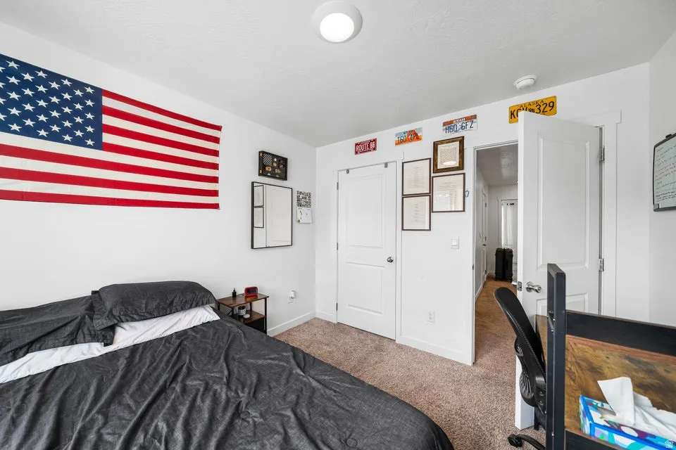 Spacious bedroom featuring plush black bedding, recessed ceiling lighting, and ample closet storage with white panel doors