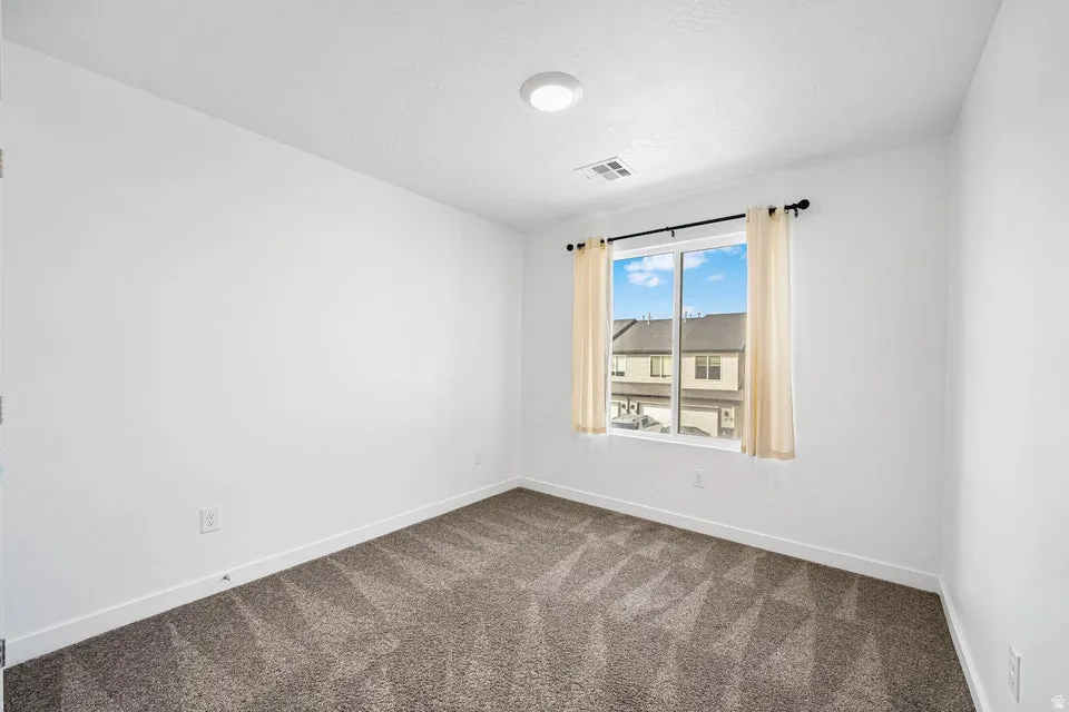 Bright interior space featuring a window with white trim, recessed lighting, white baseboards, and patterned carpeting