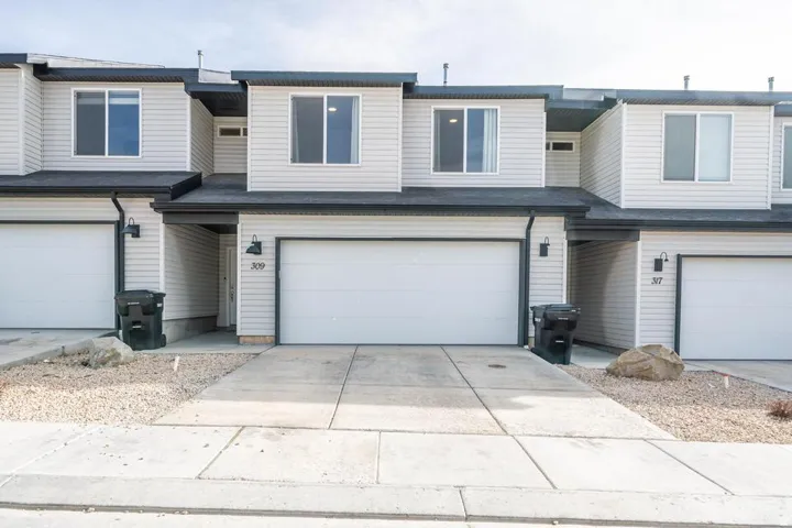 Contemporary townhome exterior featuring light gray horizontal siding and dark trim accents