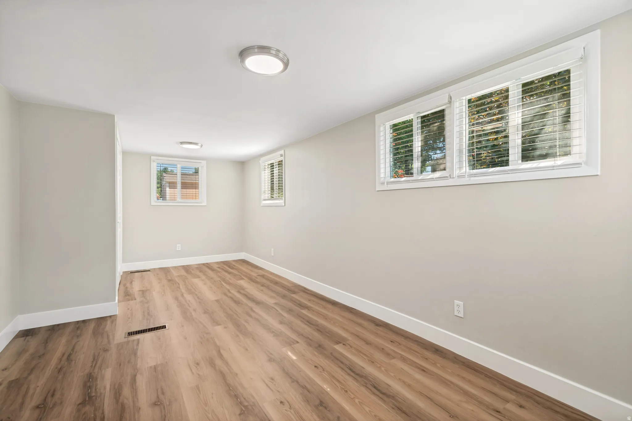 Bright room featuring wood-finish flooring, light neutral wall paint, and white trim