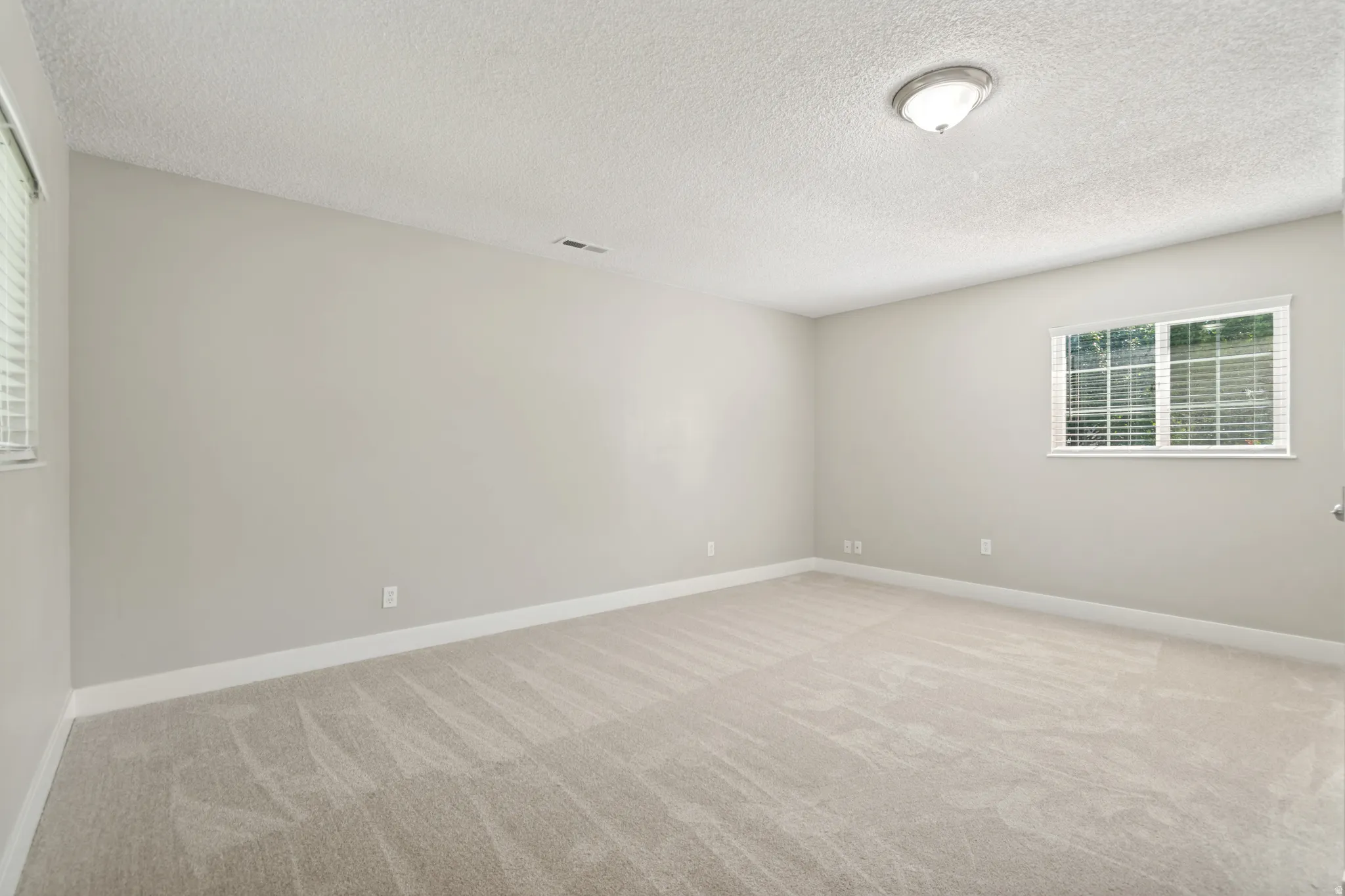 Spacious secondary bedroom with neutral wall finishes, recessed ceiling lighting, and wood-finish flooring throughout