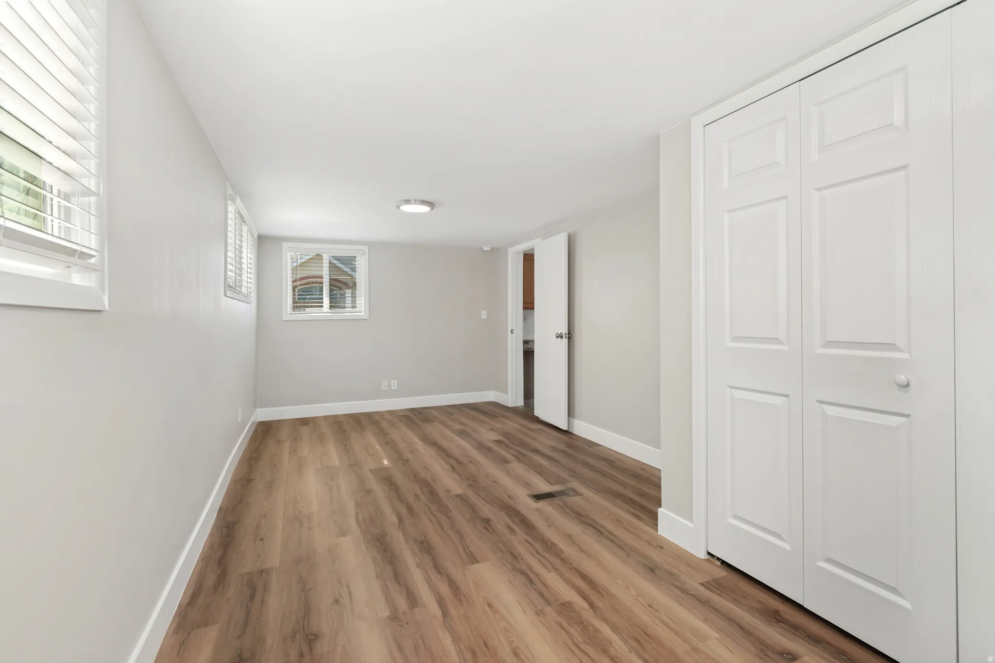 Spacious room featuring wood-finish flooring, white baseboards, and light gray walls
