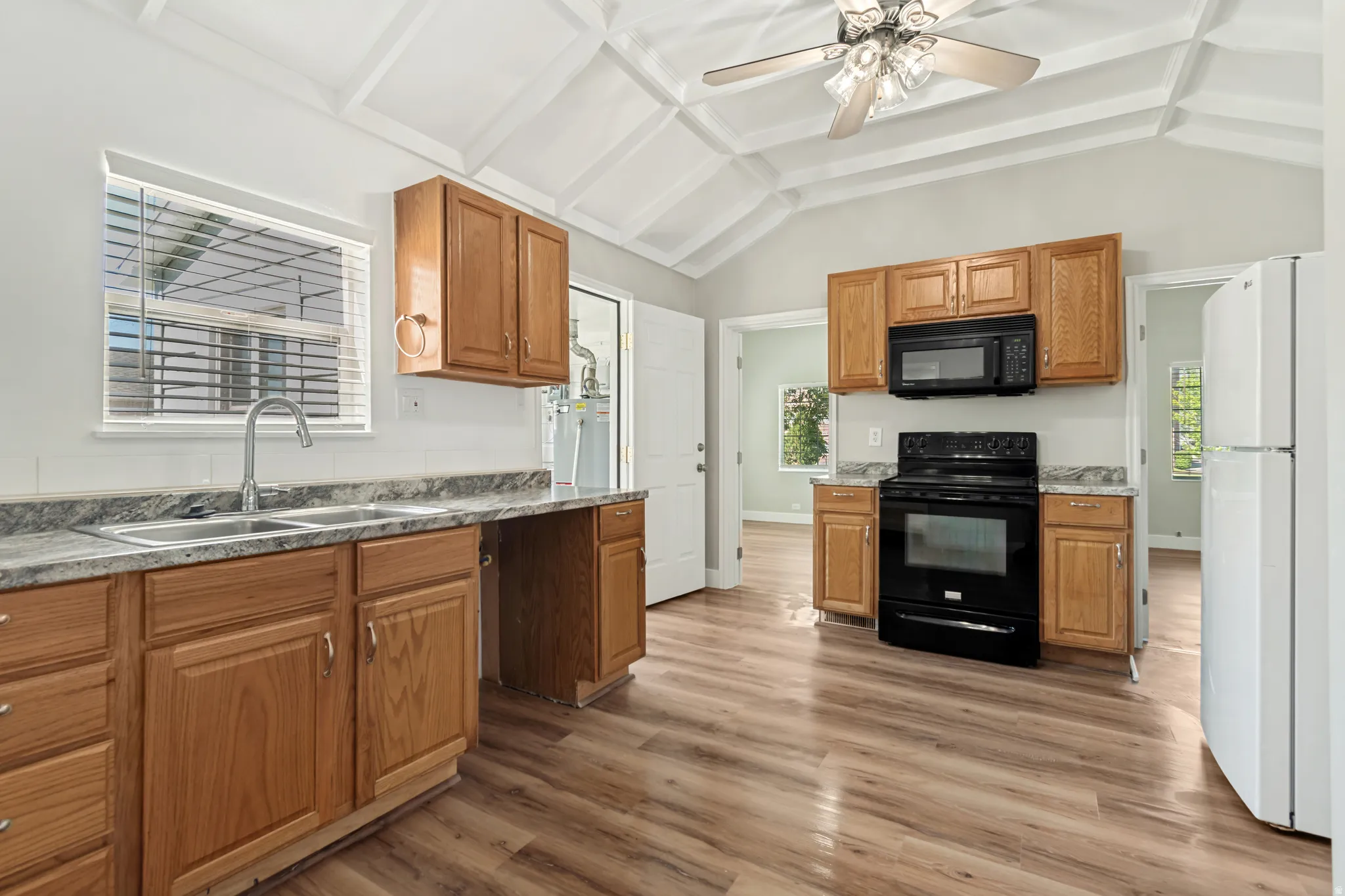 Bright, open kitchen featuring warm wood cabinetry, stainless steel appliances, and a large center island with seating
