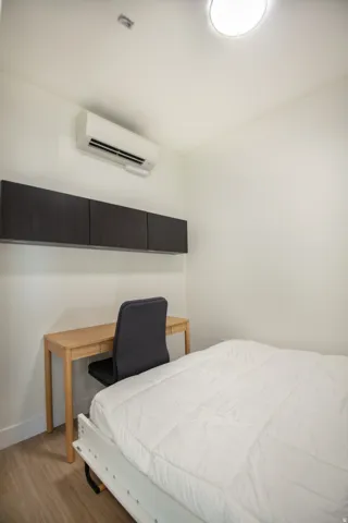 Bright interior space featuring a wall-mounted AC unit, dark wood-finish cabinetry, and light wood-finish flooring