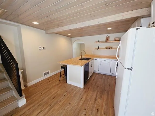 Contemporary kitchen space featuring wood-finish flooring, white cabinetry, wood countertops, and a wood-paneled ceiling with recessed lighting
