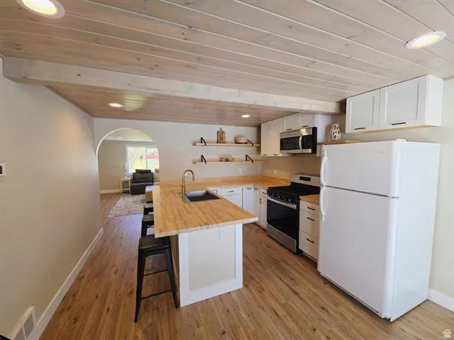 Kitchen featuring wood-finish flooring, white cabinetry, a built-in microwave, and a gas range