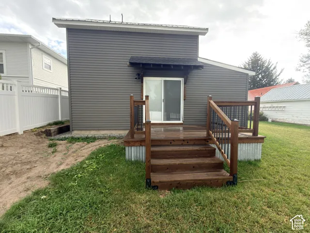 Exterior featuring horizontal lap siding, a raised wood deck with metal balusters, and corrugated metal skirting