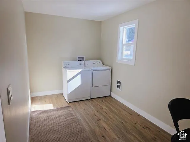 Laundry area featuring wood-finish flooring, light neutral-toned walls, and white baseboards
