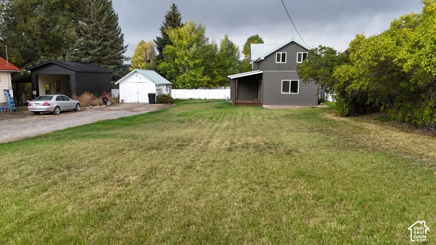Expansive lot featuring a gravel driveway, detached garage, secondary storage structure, and a fenced perimeter