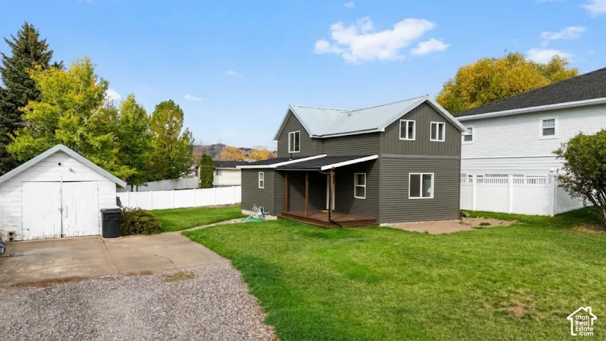 Two-story residence featuring horizontal siding, a covered porch, a detached garage, and a fenced yard with established landscaping